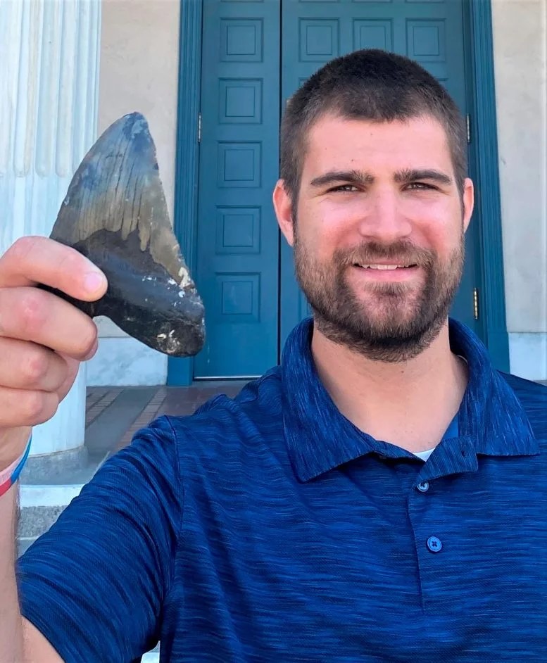 Megalodonte: un nuovo studio rivela come era fatto 2 Phillip Sternes, biologo della UC Riverside e primo autore dell'articolo, tiene in mano un dente di Megalodonte. Crediti: Douglas Long/Accademia delle Scienze della California
