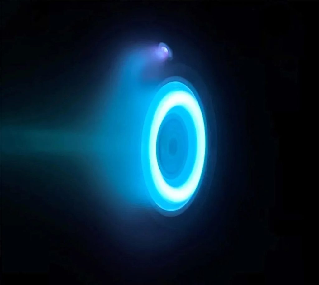 Psyche della NASA in viaggio verso un asteroide ricco di metalli 1 Un propulsore elettrico Hall, identico a quelli che verranno utilizzati per azionare la navicella spaziale Psyche della NASA, è in fase di test presso il Jet Propulsion Laboratory della NASA. Il bagliore blu è prodotto dal propellente allo xeno, un gas neutro utilizzato nei fari delle auto e nei televisori al plasma. Credito: NASA/JPL-Caltech
